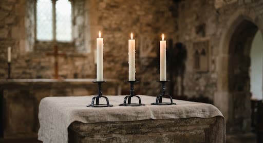 White beeswax candles in iron holders on a chapel altar